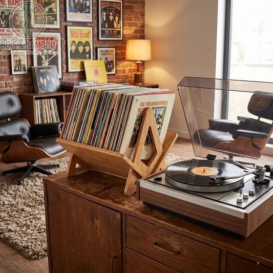 Support de disque vinyle en bambou situation 1. Un support design en bambou exposant une collection de vinyles à côté d'une platine vintage, dans un salon rétro chaleureux avec fauteuils en cuir.