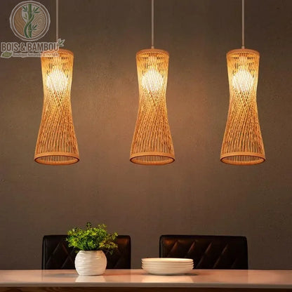 Suspension lanterne en bambou au tressage vertical élancé et cintré, créant une silhouette élégante et moderne. Son design ajouré permet une diffusion lumineuse douce et chaleureuse, idéale pour illuminer une table de salle à manger ou un comptoir avec une touche d'artisanat naturel.