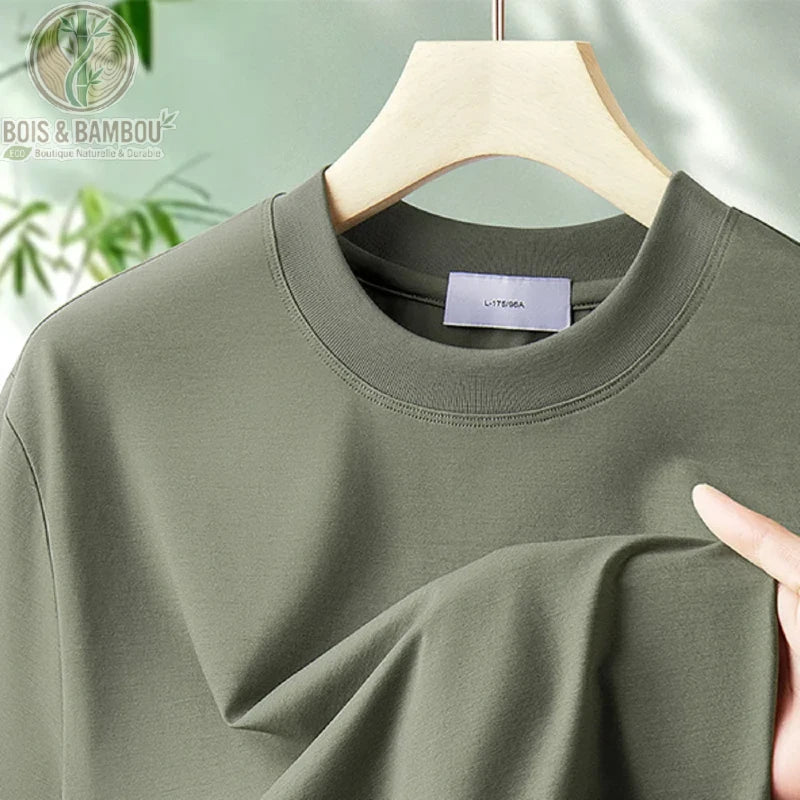 T-shirt antibactérien en fibre de bambou. Gros plan sur le col d'un t-shirt vert olive suspendu à un cintre en bois, montrant une texture de tissu lisse et de haute qualité.