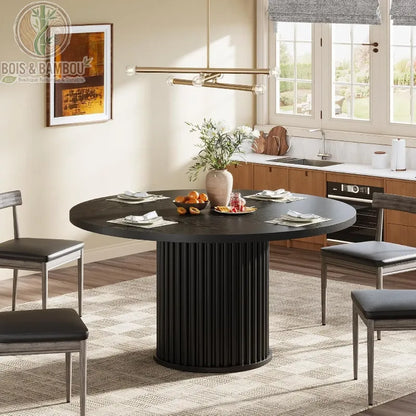 Table a manger en bois massif ovale 6 personnes noir. Table de salle à manger noire au design contemporain avec pied central cannelé, dressée pour six personnes dans une cuisine ouverte moderne.
