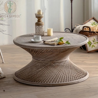 Table basse ronde en rotin et bambou grand . Zoom sur une table basse circulaire en rotin tressé au design en sablier, accueillant une tasse de café, un livre et des bougies dans un cadre serein.