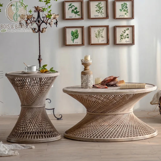 Table basse ronde en rotin et bambou. Deux tables en rotin tressé de forme sablier, une haute et une basse, décorées d'objets anciens dans un salon au style bohème et naturel.