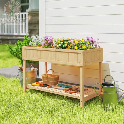 Table de Culture en Bois. Une jardinière surélevée en bois clair garnie de fleurs colorées, avec une étagère basse accueillant des outils de jardinage sur une pelouse ensoleillée.