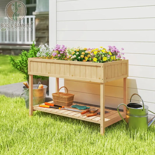 Table de Culture en Bois. Une jardinière surélevée en bois clair garnie de fleurs colorées, avec une étagère basse accueillant des outils de jardinage sur une pelouse ensoleillée.