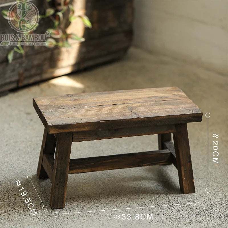 Tabouret bas en bois petit. Schéma technique d'un petit banc rustique en bois foncé affichant ses dimensions compactes : environ 33,8 cm de longueur, 20 cm de hauteur et 19,5 cm de profondeur.