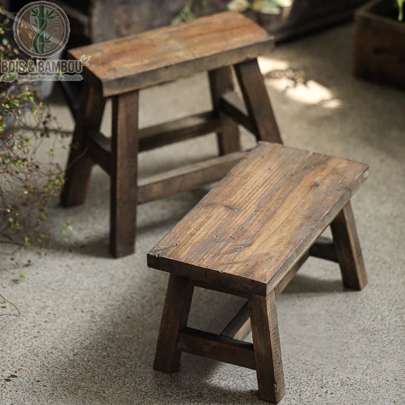 Tabouret bas en bois : lot de deux petits bancs rustiques en bois massif vieilli. Design authentique et robuste, idéal comme assise d'appoint ou support décoratif pour plantes.