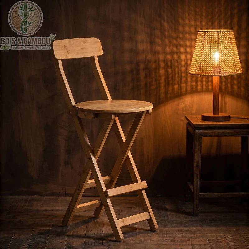 Tabouret de Bar en Bambou situation 1. Tabouret de bar pliant en bambou naturel à côté d'une lampe tamisée, créant une ambiance chaleureuse et élégante dans un coin de pièce au style boisé.
