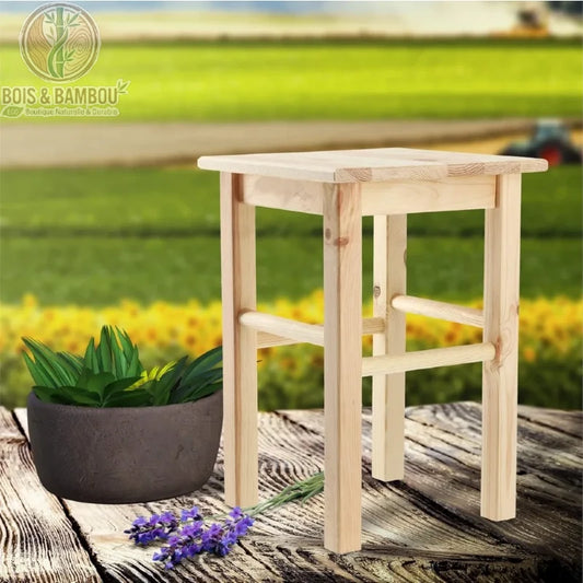 Tabouret en Pin Naturel situation. Tabouret haut classique en bois de pin clair brut avec repose-pieds, présenté en extérieur sur une table en bois avec une plante et de la lavande.