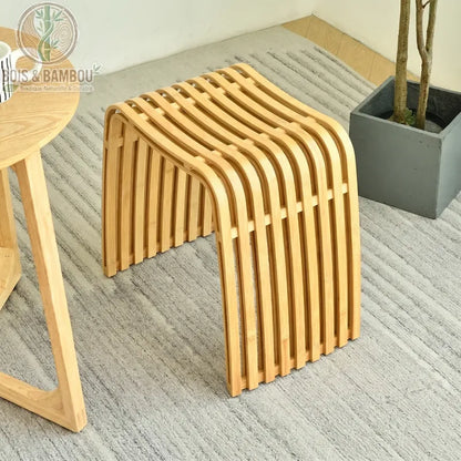 Tabouret moderne en bambou Nan classique au design incurvé à lattes, posé sur un tapis gris.
