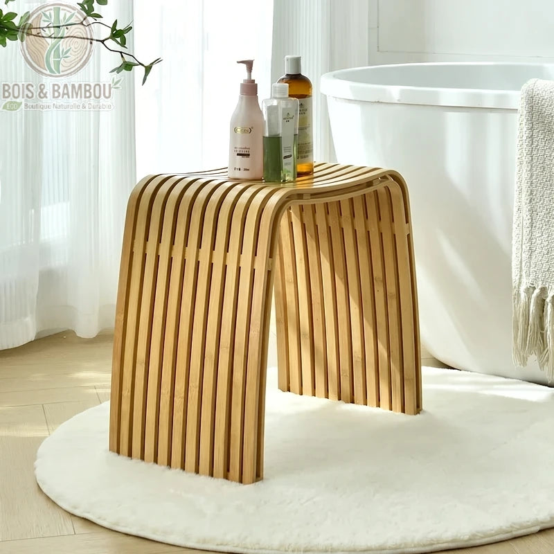 Tabouret moderne en bambou Nan luxe avec un siège incurvé à lattes, placé dans une salle de bain près d'une baignoire.