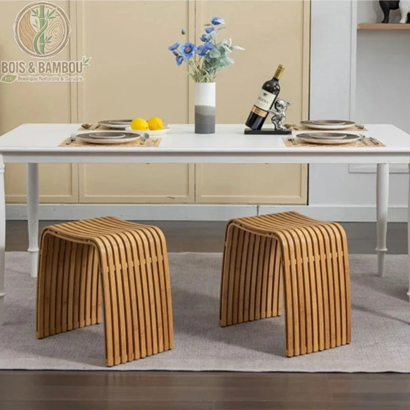 Tabouret moderne en bambou Nan situation 2 avec deux sièges incurvés à lattes placés sous une table à manger blanche.