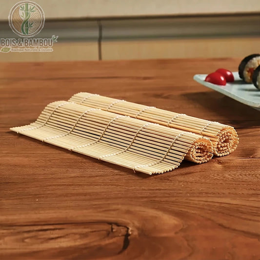 Tapis à Sushi en Bambou. Deux tapis de bambou traditionnels partiellement enroulés, posés sur une table en bois avec une assiette de sushis en arrière-plan. Ustensile de cuisine japonais.