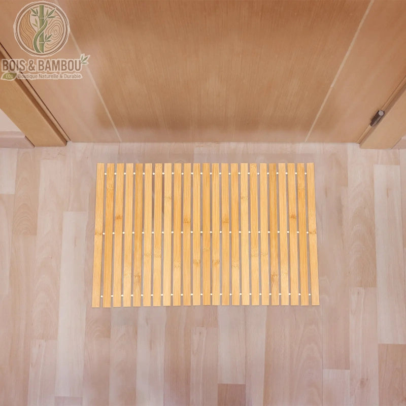 Tapis de douche pliable en bambou composé de fines lattes de bois clair assemblées parallèlement pour offrir une surface stable et aérée.