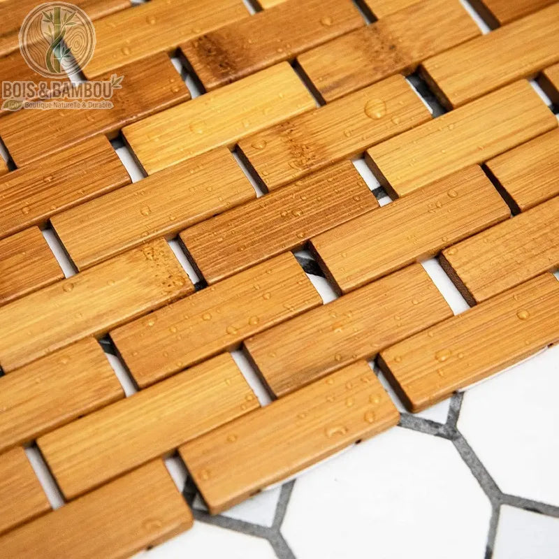 Tapis en bambou naturel conçu avec des lattes rectangulaires assemblées de manière articulée, rappelant la structure d'un parquet ou d'un caillebotis.