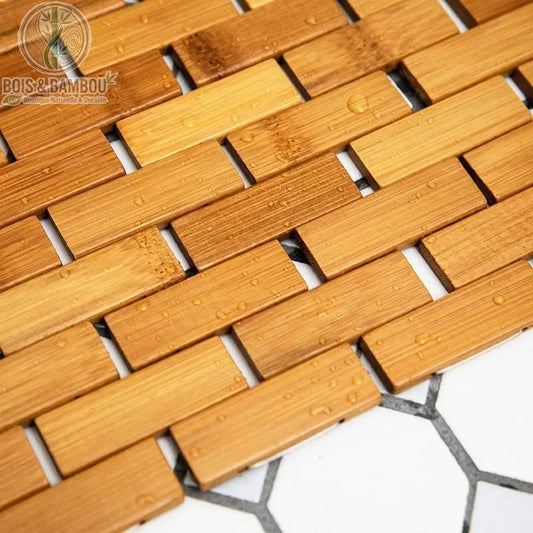 Tapis en bambou naturel conçu avec des lattes rectangulaires assemblées de manière articulée, rappelant la structure d'un parquet ou d'un caillebotis.