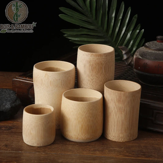 Tasse en bambou carbonisé rétro. Un ensemble de cinq tasses cylindriques en bambou de différentes tailles, disposées sur un plateau en bois sombre à côté d'une théière ancienne.