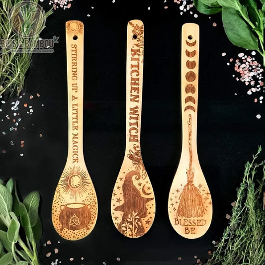 Ustensiles de Cuisine de Noël. Trois cuillères en bambou gravées de motifs mystiques (chaudron, chapeau de sorcière, balai) sur fond noir entourées d'herbes aromatiques et de sel.