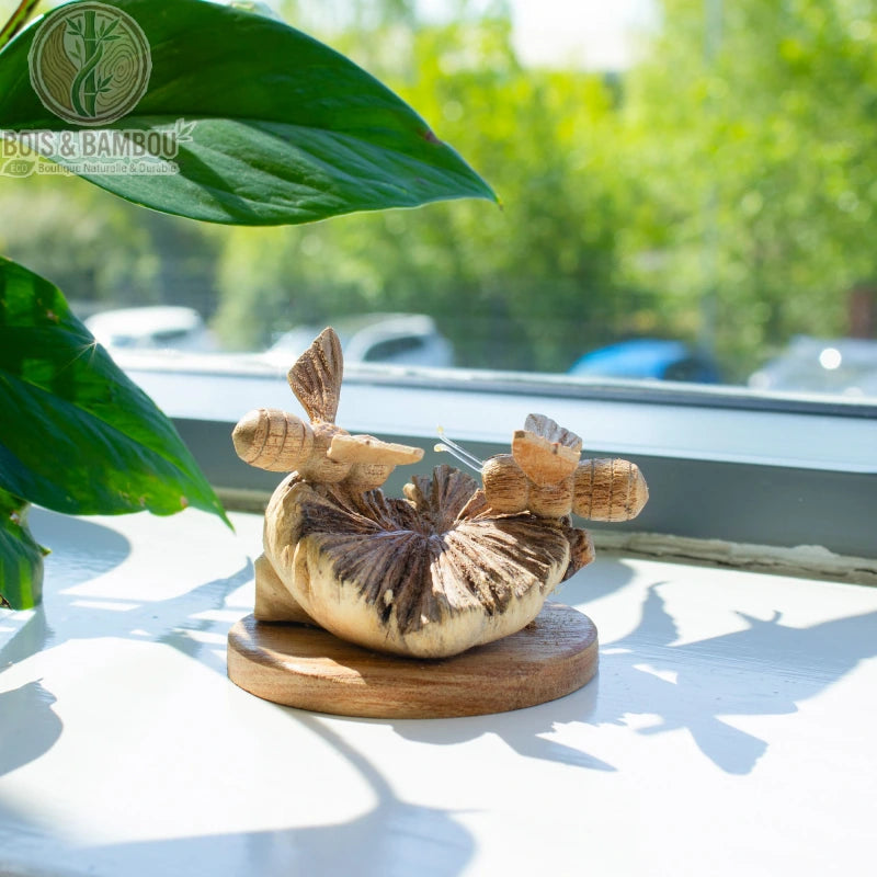 Sculpture abeilles en bois posée sur un rebord de fenêtre
