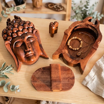 Boîte à bijoux en bois sculpté tête de Bouddha, artisanat balinais, posée avec bijoux et autres boîtes en bois