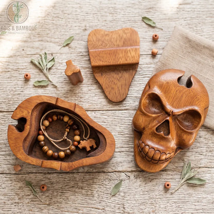 Boîte à bijoux en bois sculpté motif crâne, ouverte avec bracelet en perles de bois et pendentif éléphant