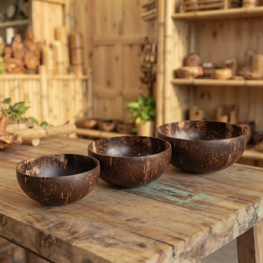 Bol en noix de coco naturel en trois contenances, posés sur une table en bois brut dans une boutique en bambou