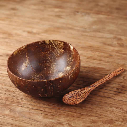 Bol en noix de coco naturel fait main avec cuillère en bois, sur une table en bois brut
