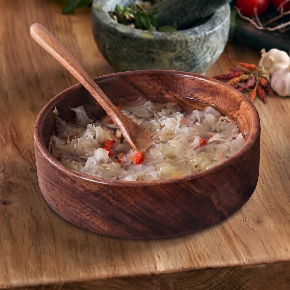 Bol en noyer massif 20 cm, rempli d'une soupe de chou avec une cuillère en bois