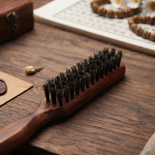 Gros plan sur les poils de sanglier et le manche en bois sculpté de la brosse à cheveux
