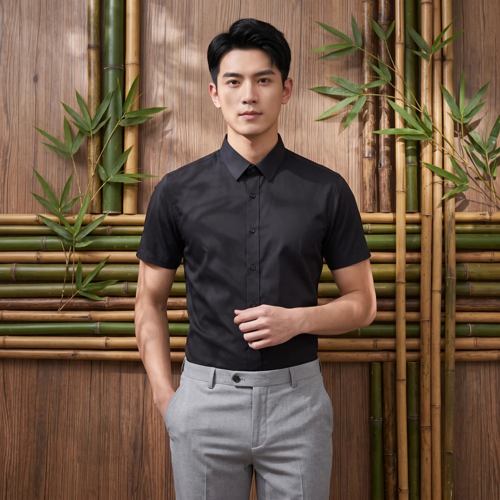 Homme portant une chemise en fibre de bambou manches courtes noire, devant un mur de bambou