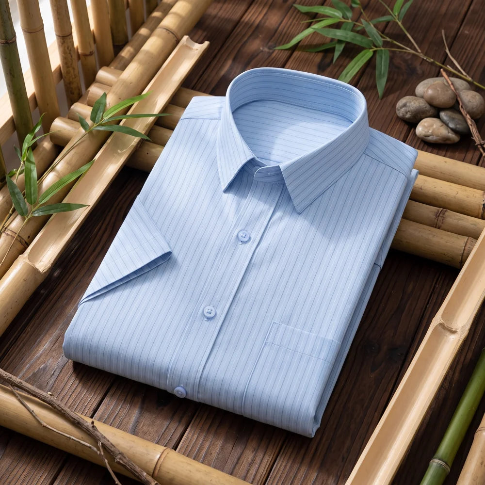Chemise homme en fibre de bambou manches courtes bleu clair à fines rayures, pliée sur fond bambou naturel