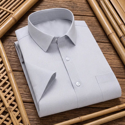 Chemise homme en fibre de bambou manches courtes grise à fines rayures, pliée sur fond bambou naturel