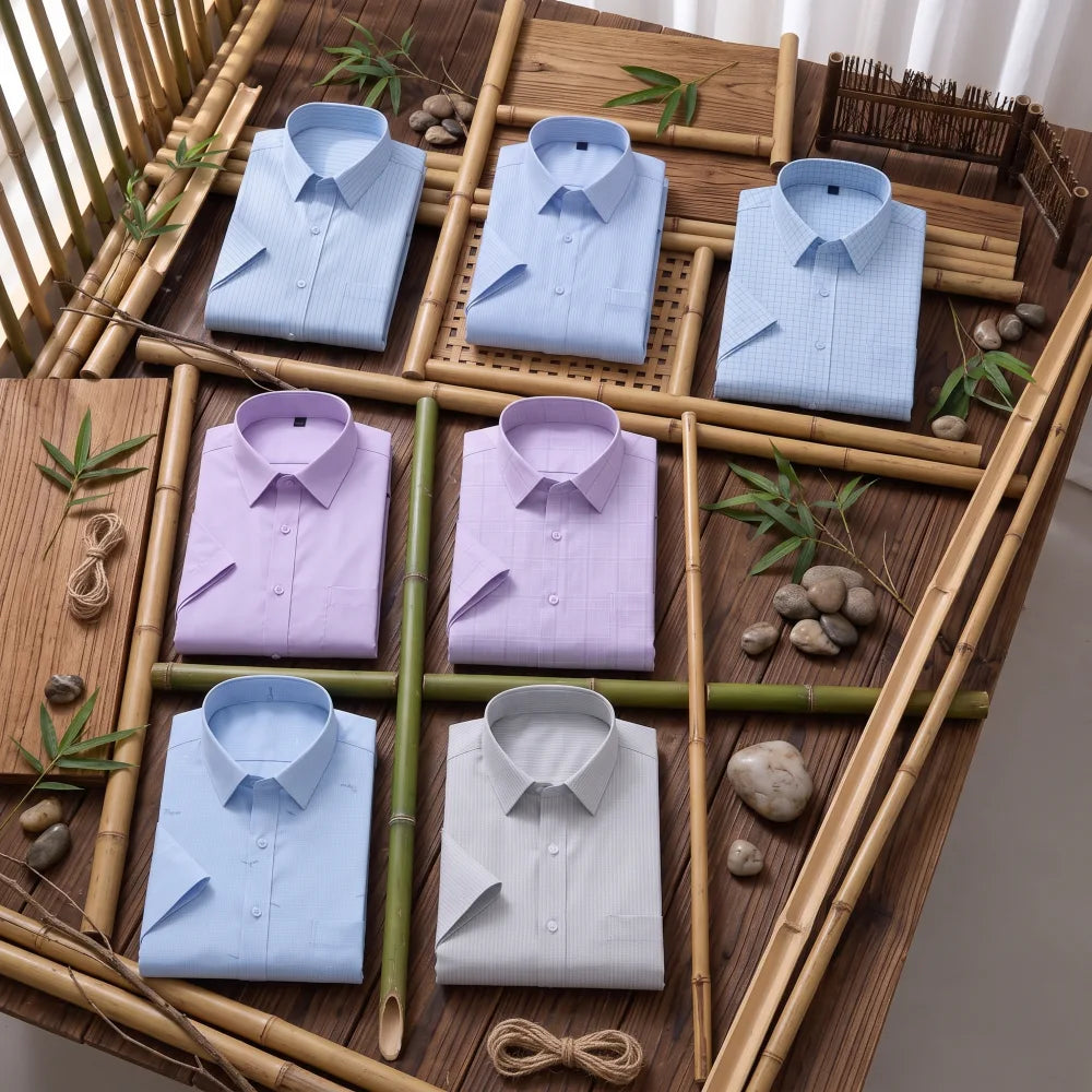Six chemises homme en fibre de bambou manches courtes à motifs, fines rayures et carreaux dans les tons bleu clair, mauve et gris, pliées sur fond bambou