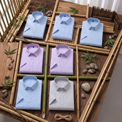 Six chemises homme en fibre de bambou manches courtes à motifs, fines rayures et carreaux dans les tons bleu clair, mauve et gris, pliées sur fond bambou