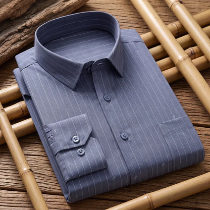 Chemise homme en fibre de bambou à fines rayures gris-bleu, pliée près d'un morceau de bois flotté