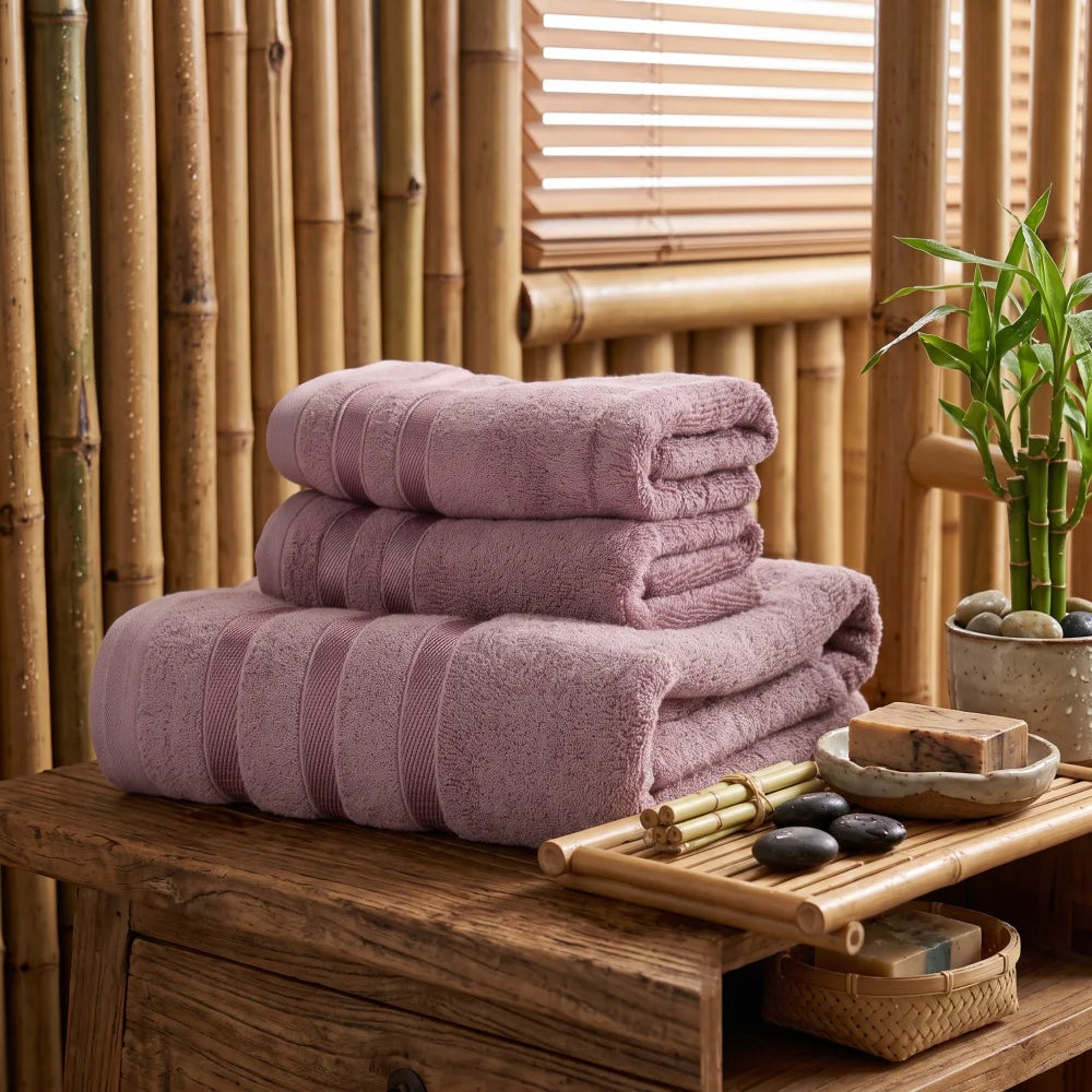Coffret de 3 serviettes en bambou coloris pourpre, pliées et empilées dans une salle de bain en bois et bambou