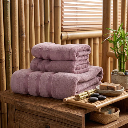 Coffret de 3 serviettes en bambou coloris pourpre, pliées et empilées dans une salle de bain en bois et bambou