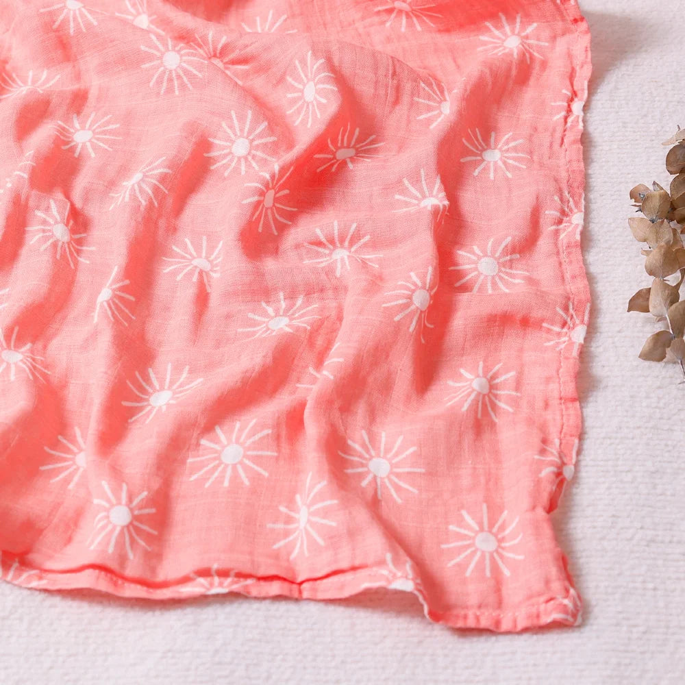 Couverture légère bébé en coton et bambou, motif soleils blancs sur fond corail