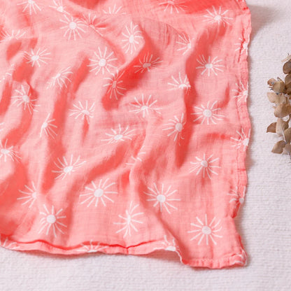 Couverture légère bébé en coton et bambou, motif soleils blancs sur fond corail