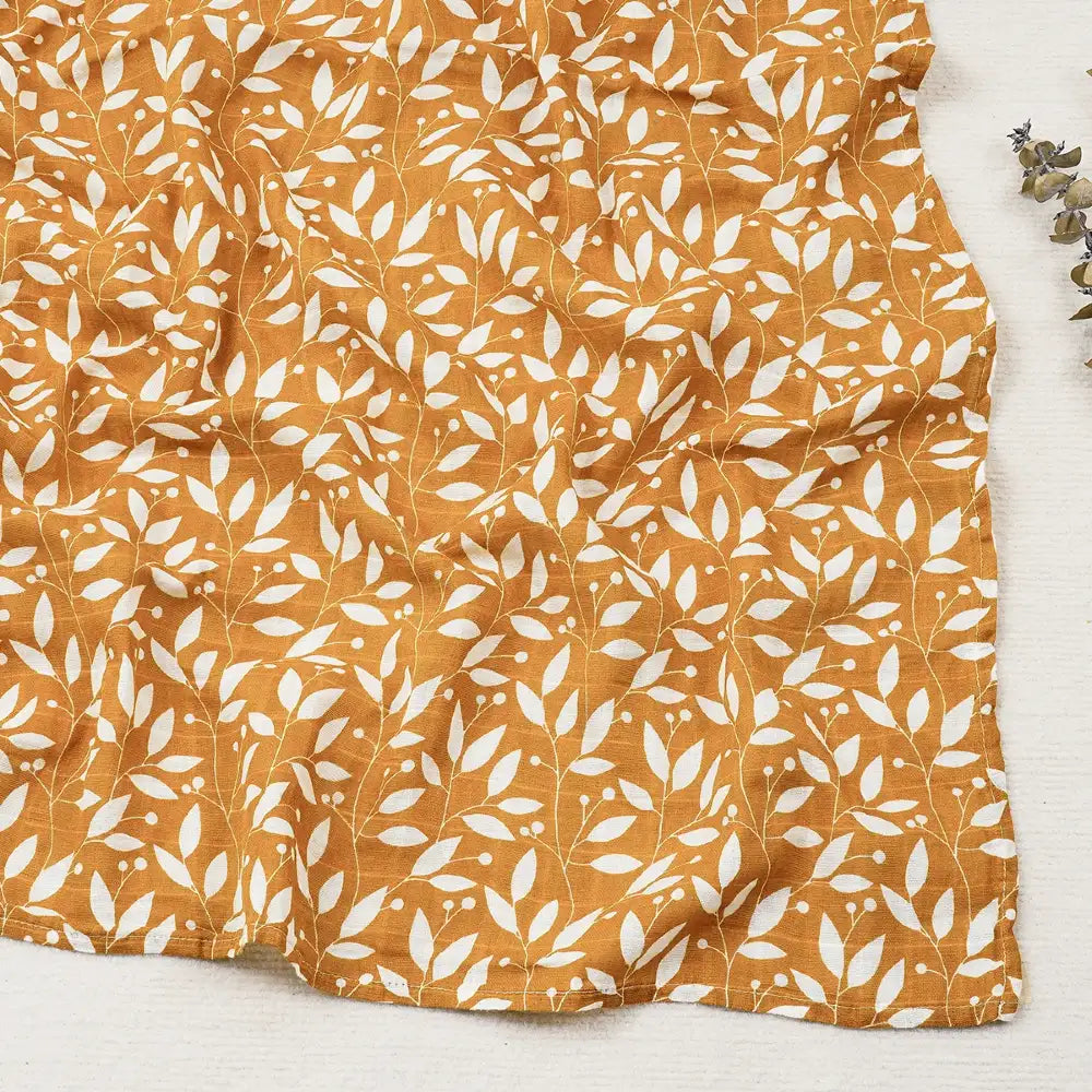 Couverture légère bébé en coton et bambou, motif feuillage blanc sur fond jaune moutarde