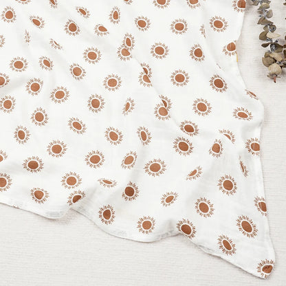 Couverture légère bébé en coton et bambou, motif soleils orange sur fond blanc