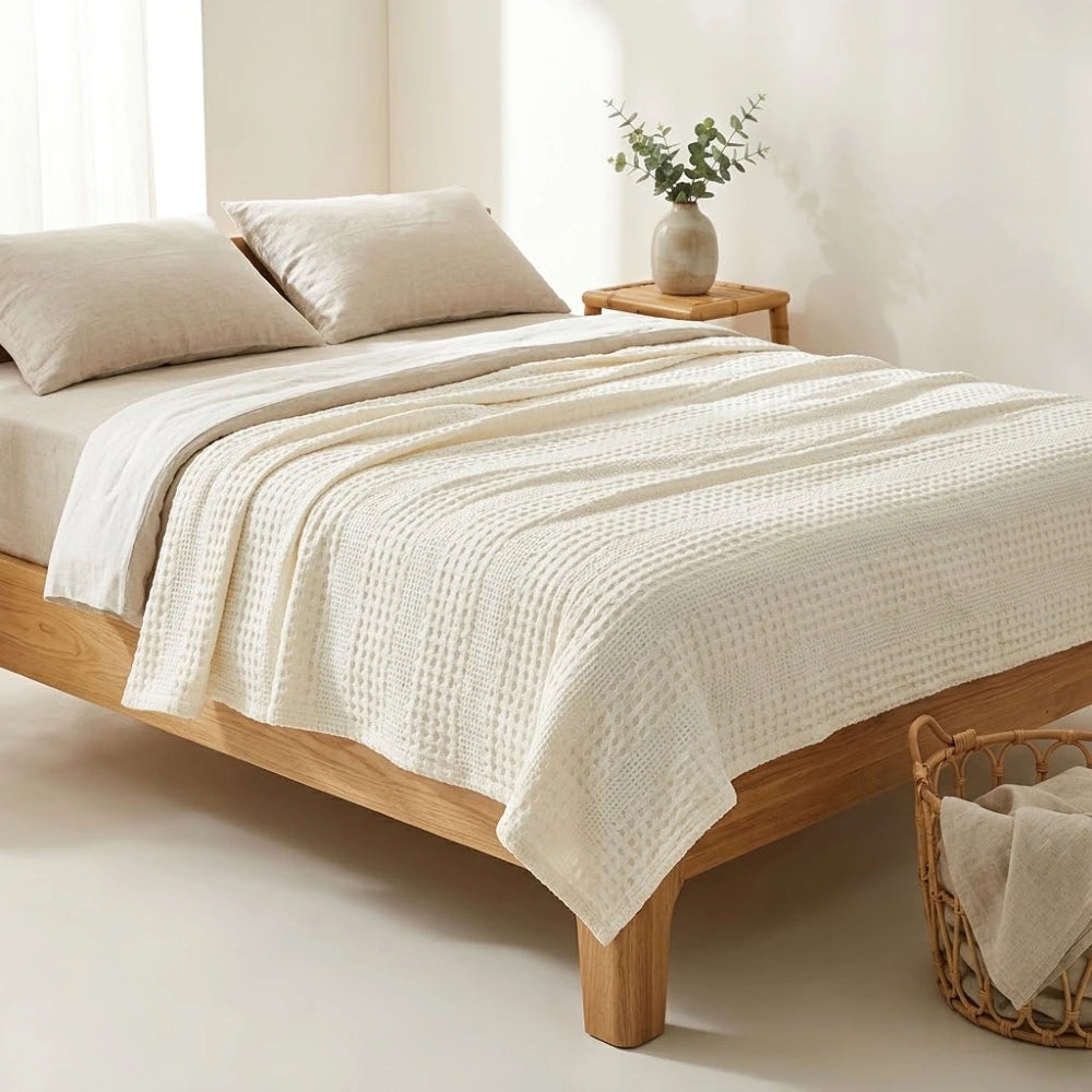 Couverture gaufrée bambou coton nid d'abeille sur un lit, coloris blanc