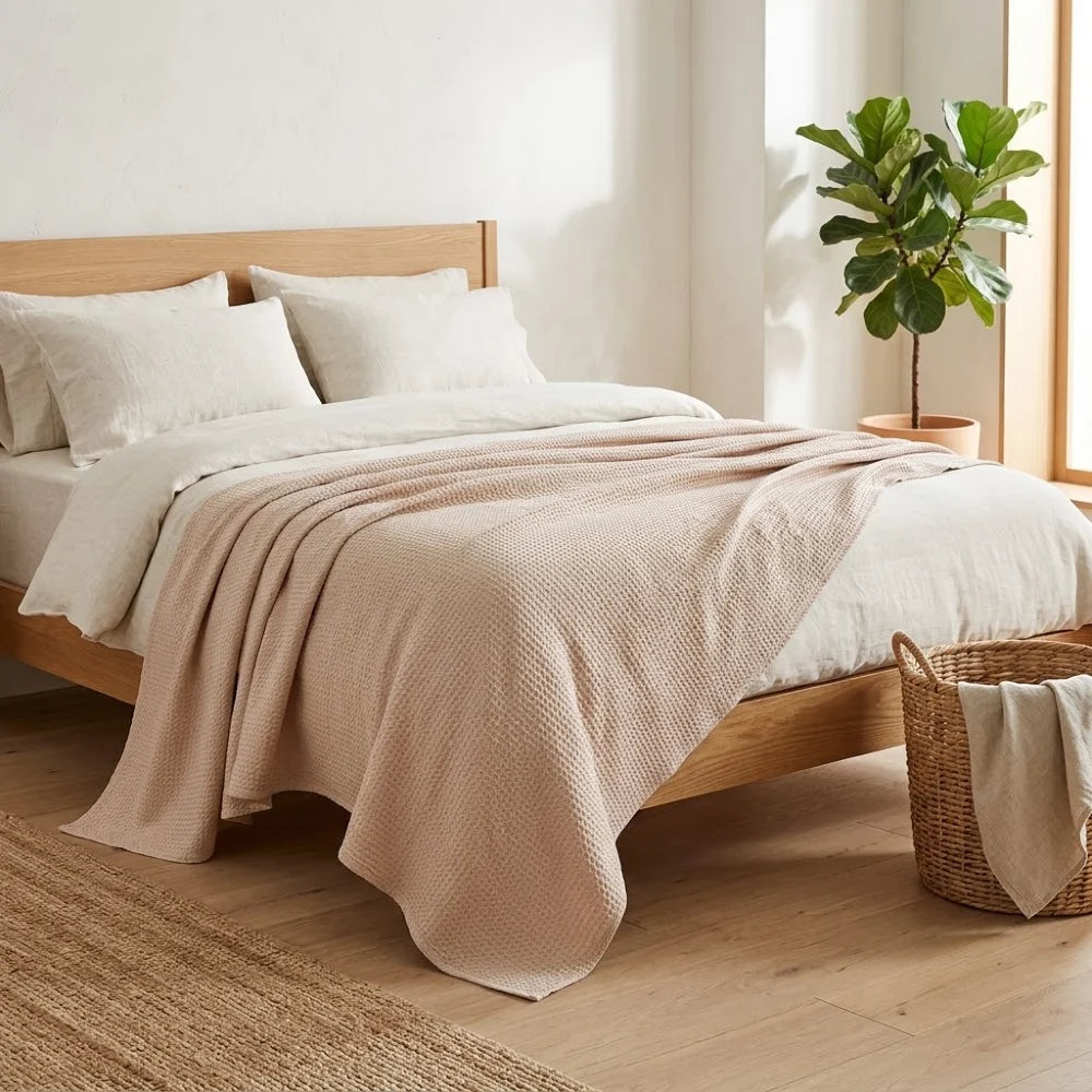 Couverture rafraîchissante en coton bambou, coloris beige, posée sur un lit avec linge en lin