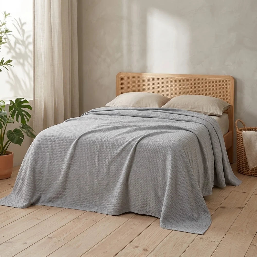 Couverture rafraîchissante en coton bambou, coloris gris, posée sur un lit en bambou clair