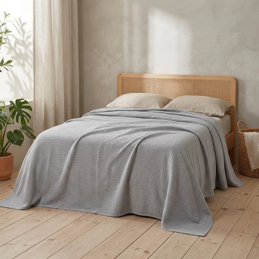 Couverture rafraîchissante en coton bambou, coloris gris, posée sur un lit en bambou clair