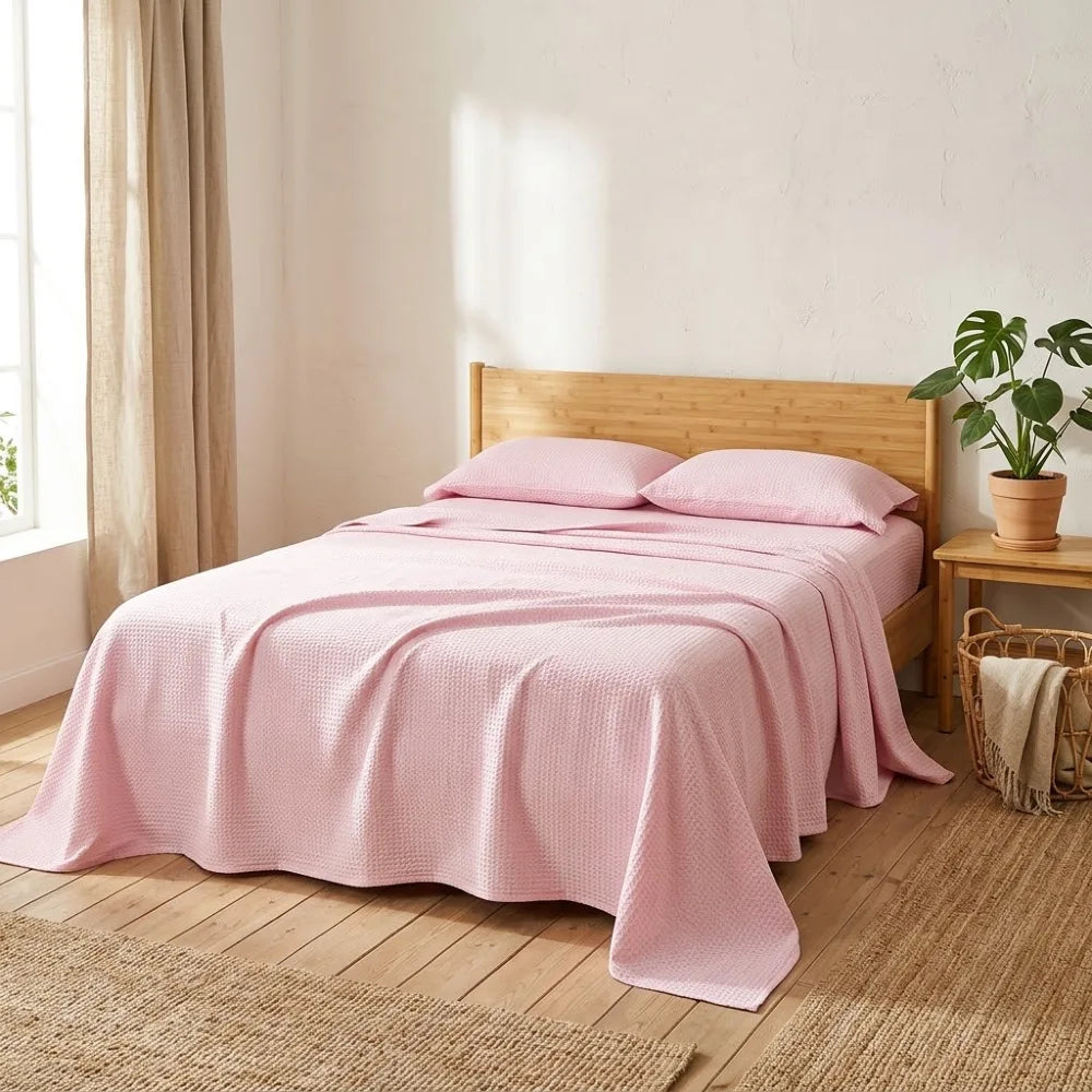 Couverture rafraîchissante en coton bambou, coloris rose, posée sur un lit en bambou naturel