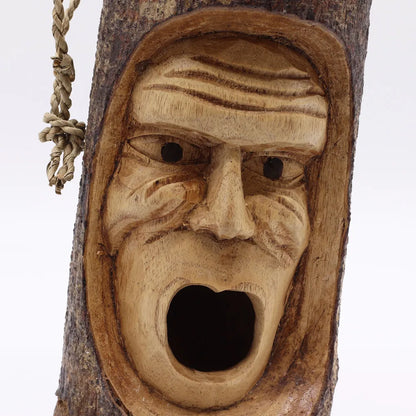 Détail du visage grincheux sculpté à la main, bouche ouverte formant le trou d'envol