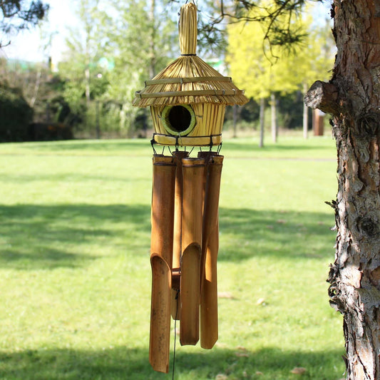 Détail du nichoir en jonc tressé et toit en chaume avec les 4 tubes de bambou du carillon
