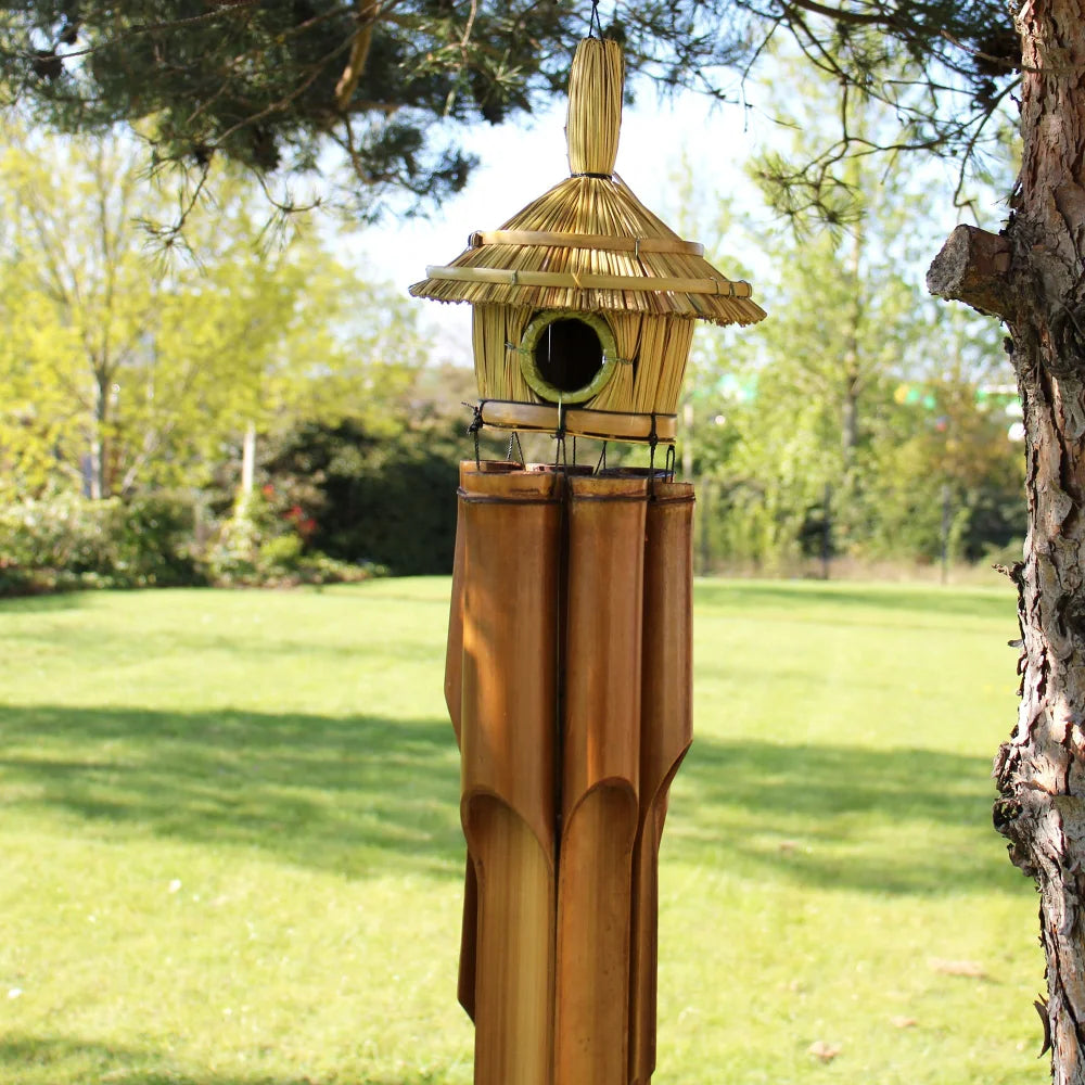 Détail du grand nichoir en jonc tressé et toit en chaume avec les 6 tubes de bambou du carillon