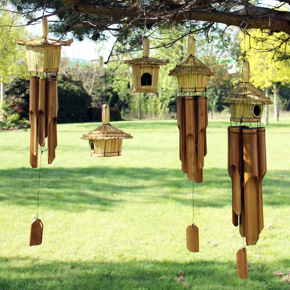 Nichoir à oiseaux en jonc rond suspendu avec des carillons en bambou dans un arbre de jardin