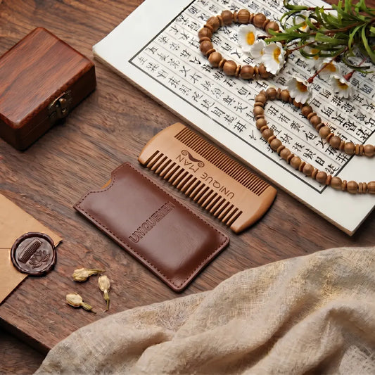 Peigne à barbe en bois double face avec étui en cuir, posé sur un bureau en bois avec parchemin calligraphié et perles